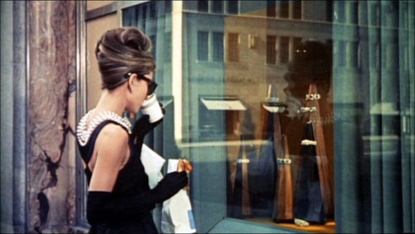 Audrey Hepburn looking at a Tiffany's window, sipping a coffee