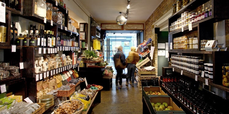 interior of shop with fruits and vegetables in baskets, shelves of jars
