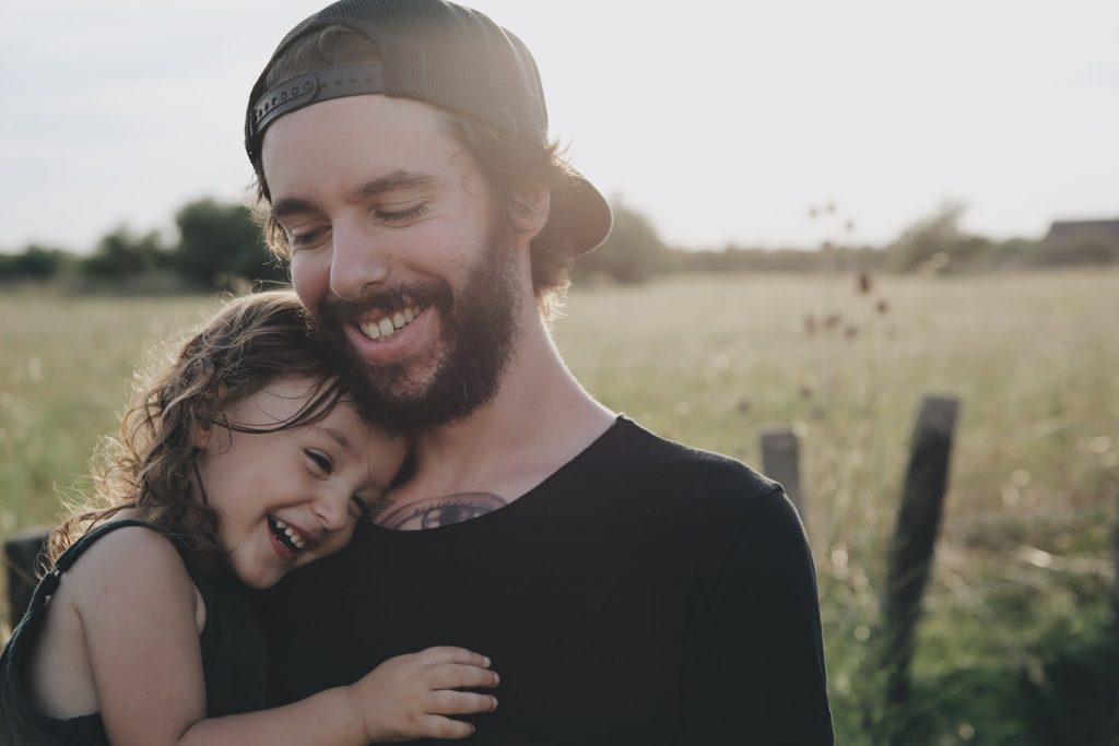 Farther holding is daughter, with a countryside background