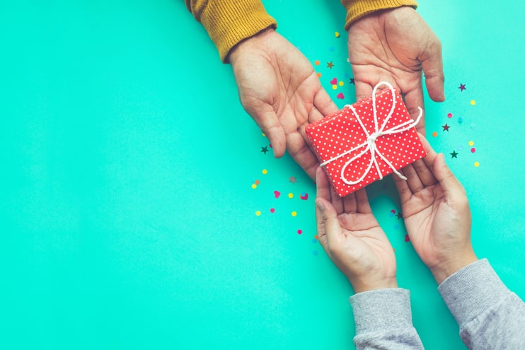 Hands exchangina red gift on a blue background