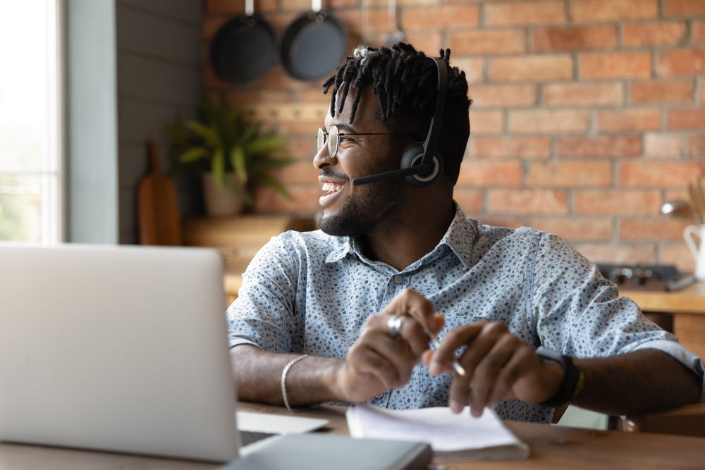 Smiling man sitting at a work desk with headphones on