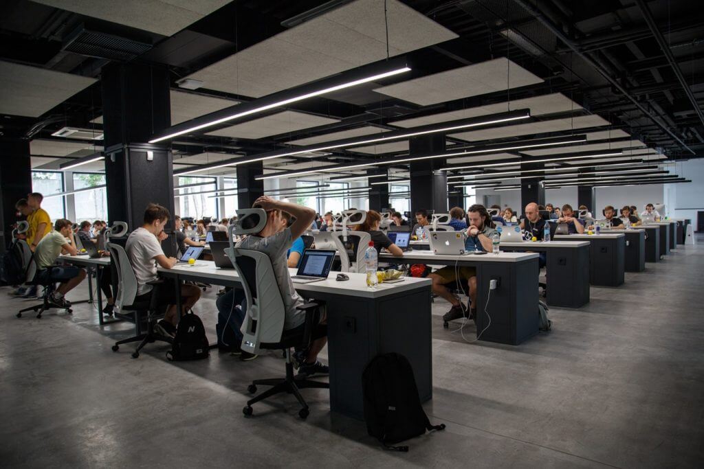 A large shared office space full of professionals working at laptops 