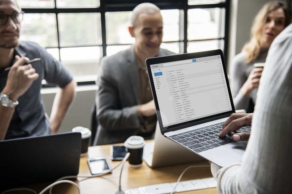 A group of business professionals working on a desk surrounded by laptops and devices