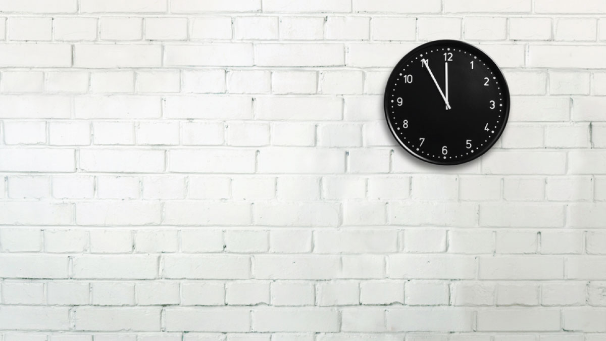 Photograph of a white brick wall with a black clock hanging on it