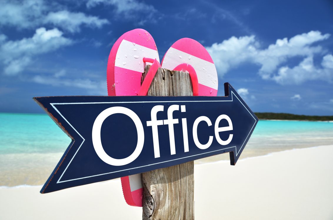 Sign pointing to "office" on the beach with flipflops hanging from the back of the sign